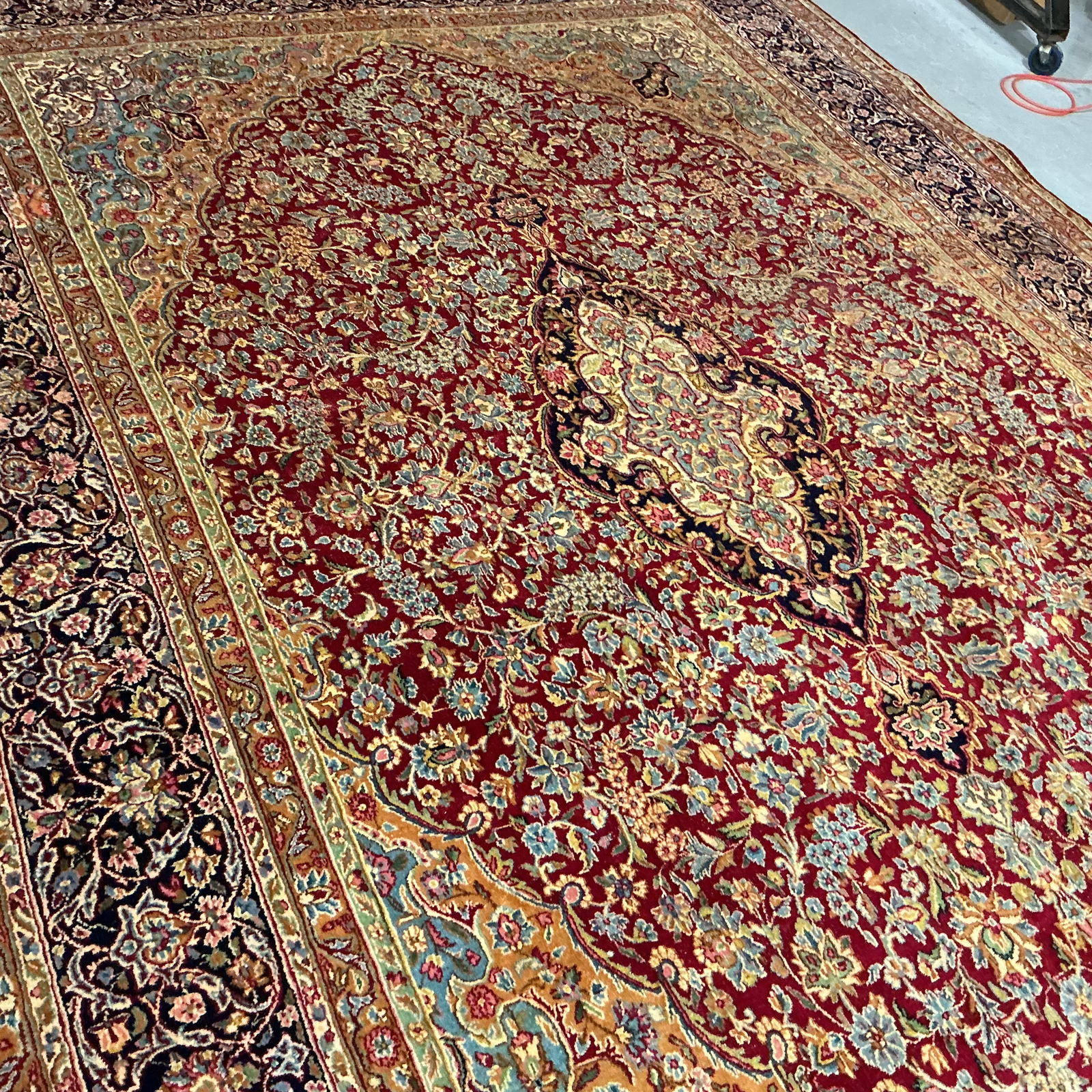 The same medallion after cleaning, the cream and gold palmette reading crisply against the navy and red